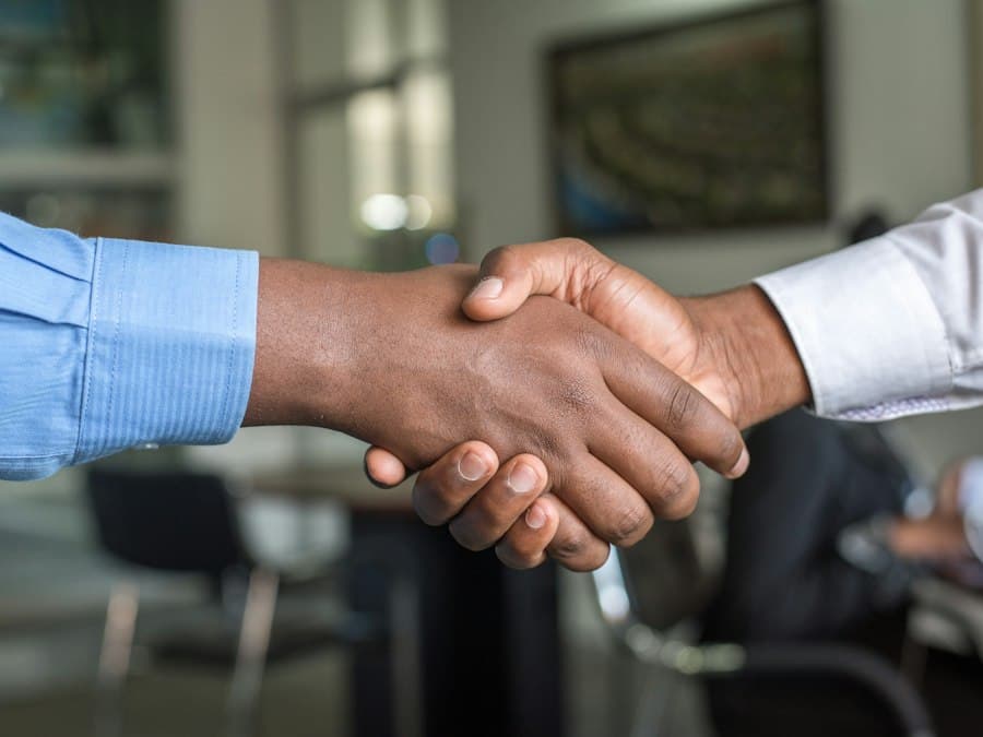 Two people shaking hands over a signed property agreement